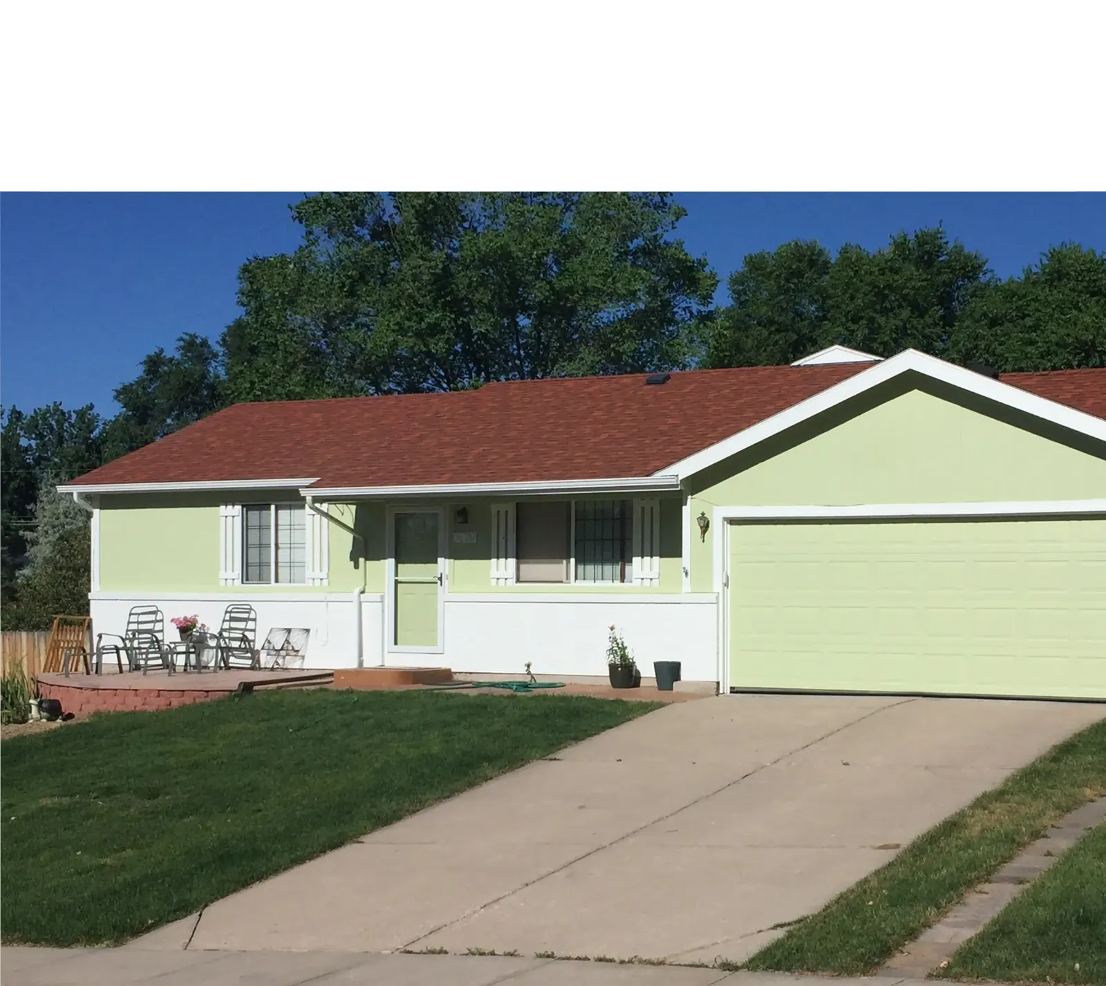 Single-story ranch home painted light green with white trim and garage door