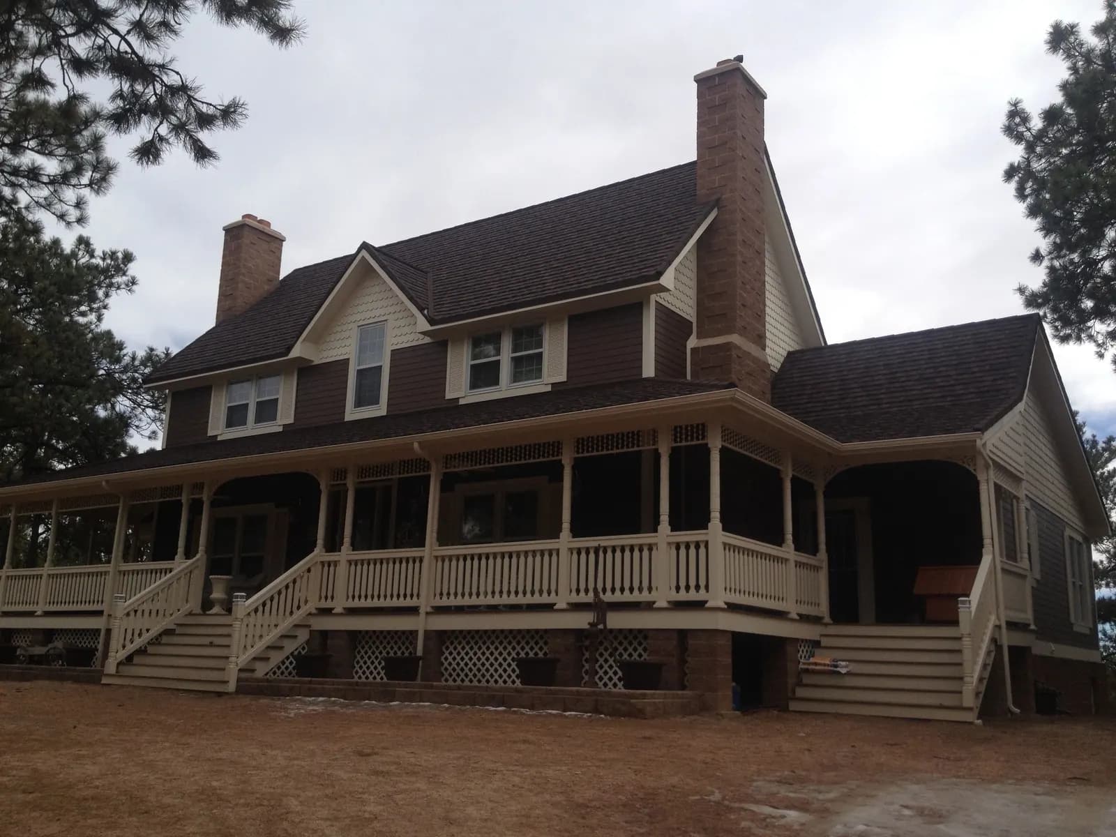 Large brown two-story house with cream trim and a covered wraparound porch
